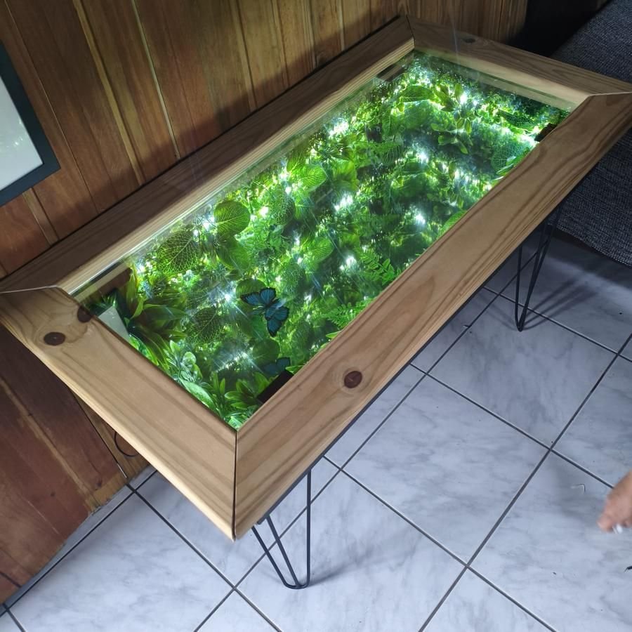Mesa Jardim Encantado: folhagem iluminada por microLEDs sob tampo de vidro, com moldura de madeira